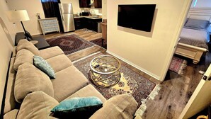 A modern living room with a sofa, coffee table, and a flat-screen TV mounted on the wall. - Sherman Oaks Cozy Guest House  (Sherman Oaks)
