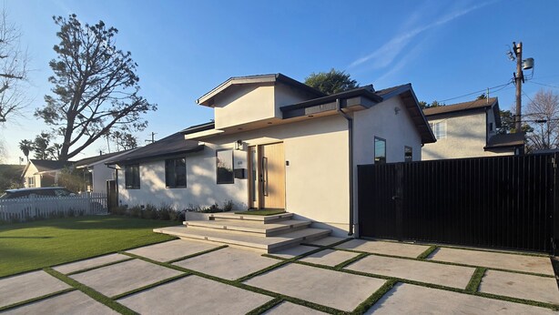 A modern two-story house with a flat roof, a front porch, and a black metal fence. - Sherman Oaks Cozy Guest House  (Sherman Oaks)