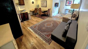 A spacious living area with a large rug, a sofa, and a dining table with chairs. - Sherman Oaks Cozy Guest House  (Sherman Oaks)
