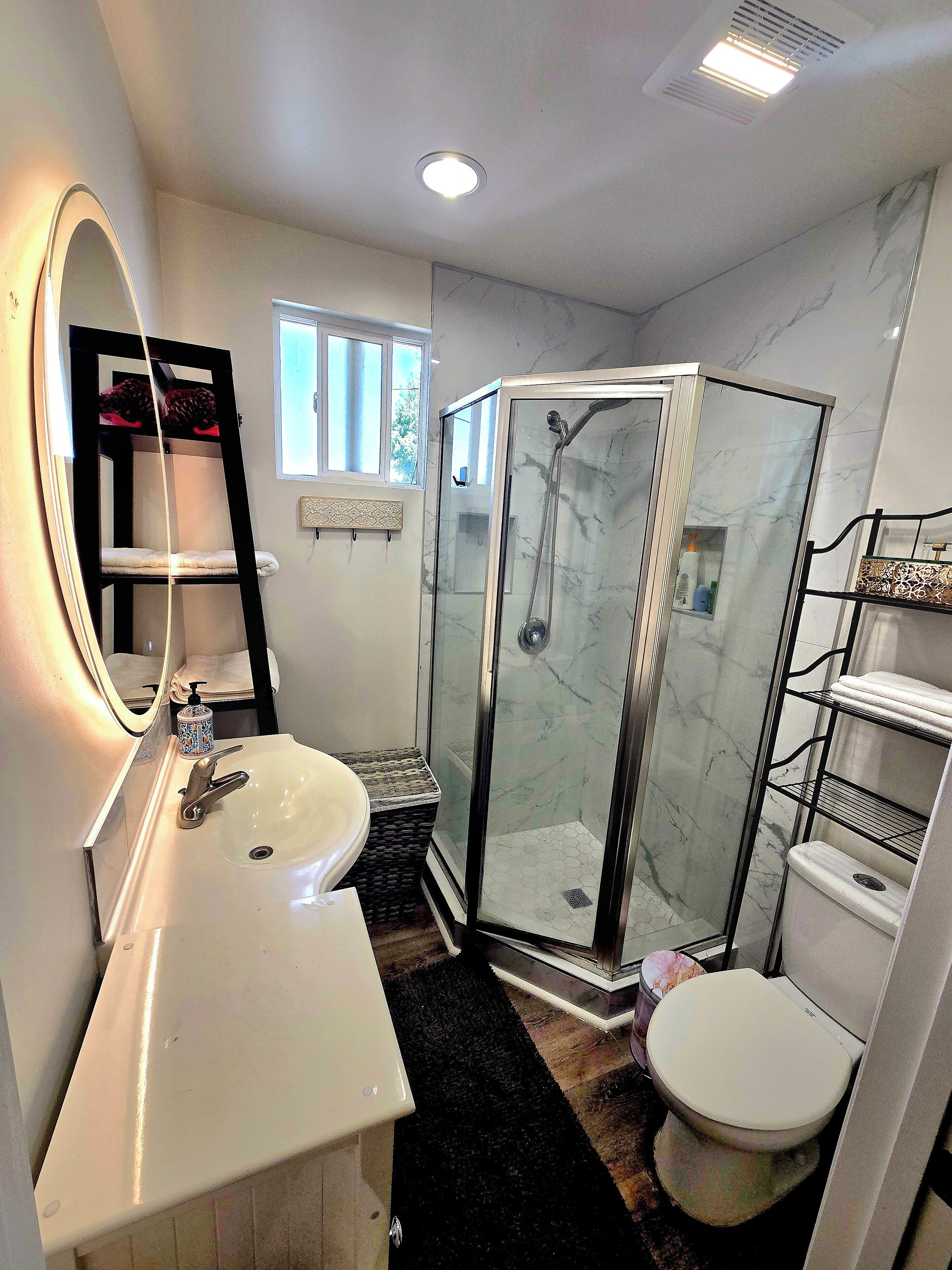 A bathroom with a white sink, a mirror, a glass-enclosed shower, and a toilet.