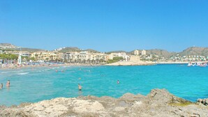 A coastal beach scene with clear blue waters, rocky shoreline, and buildings in the background. - Villa Sun Carlos by Solidays - Benissa, Costa Blanca (Benissa)