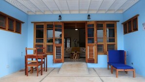 A room with a blue wall, a wooden door with glass panels, a blue chair, and a wooden table.