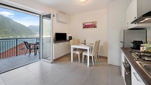 Una cocina moderna con comedor, un balcón que ofrece vistas a las montañas y un cuadro en la pared.