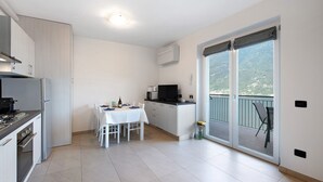 Een moderne keuken met een eethoek, een flatscreen televisie en een schuifglazen deur naar een balkon.