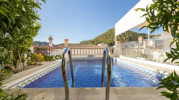 Une piscine avec vue sur un immeuble et une colline en arrière-plan.