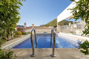 A swimming pool with a view of a building and a hill in the background.