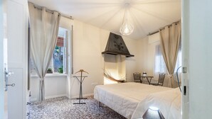 A bedroom with a bed, a table, a chair, a lamp, and a window. - Apartment "Nonna Fina" with Lake & Mountain View, Shared Pool & Wi-Fi (Tignale)