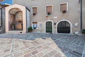 Un edificio con fachada de piedra, arcos y un patio empedrado.