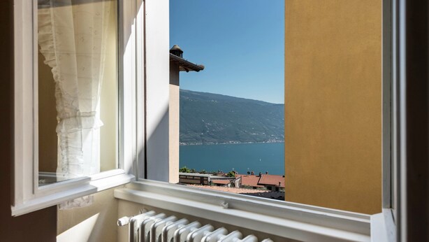 A window with a view of a mountain and a body of water. - Apartment "Nonna Fina" with Lake & Mountain View, Shared Pool & Wi-Fi (Tignale)