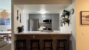 A modern kitchen with a central island, bar stools, and stainless steel appliances.