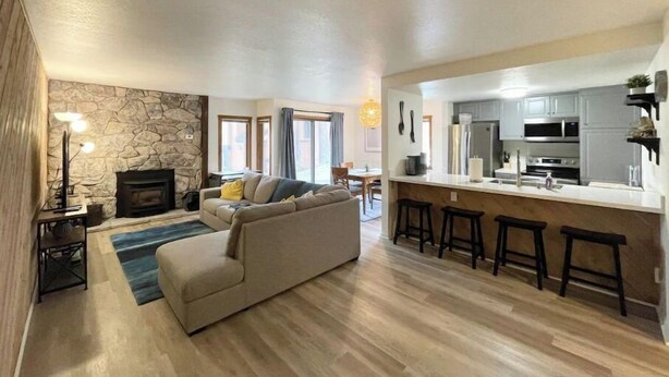 A modern living room with a stone fireplace, a sofa, and a dining area in the background.
