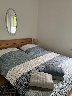 A bed with a wooden headboard, a mirror on the wall, and a bedside lamp.