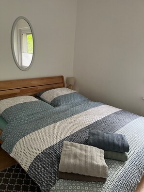 A bed with a wooden headboard, a mirror on the wall, and a bedside lamp.