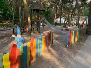 Ein Spielplatz mit Rutsche, Klettergerüsten und einem farbenfrohen Zaun.