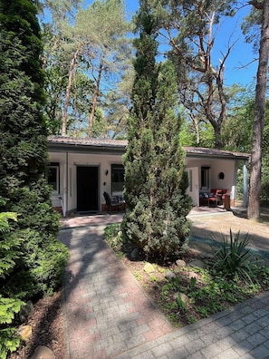 A two-story building with a covered patio area, surrounded by dense greenery and trees.