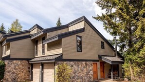 A two-story building with a stone facade, a garage, and a covered porch. - Ski In Whistler Village Townhome in Best Location Telemark (Whistler)