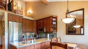 A kitchen with wooden cabinets, stainless steel appliances, granite countertops, and a dining area with a wooden table and chairs. - Ski In Whistler Village Townhome in Best Location Telemark (Whistler)