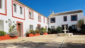A courtyard with cobblestone paving, white buildings with red trim, and a fountain. - Villa Domínguez - Typical Andalusian farmhouse (Wi-Fi,BBQ, swimmingpool,relax) (lucena)