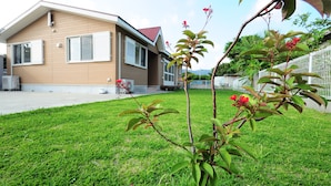 A modern two-story house with a flat roof and a well-maintained lawn. - Sun Akaishibeach no Yado (Ishigaki)