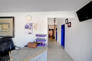 A hallway with a reception desk, a clock, and a blue door.