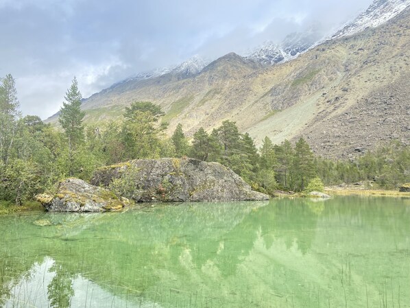 A mountain landscape with a clear lake, trees, and rocky terrain.