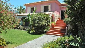 A pink villa with a stone archway, a red staircase, and a well-maintained garden. - Holiday Home in Sicily near Fontane Bianche (Terrauzza)
