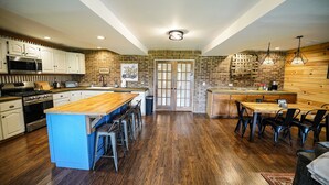 A spacious kitchen with a central island, wooden flooring, and modern appliances. - Farmhouse by the Lake with FAST Fiber Internet + Washer/Dryer! (Campton)