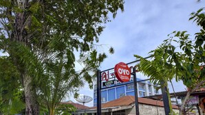A building with a blue facade, a red sign with white text, and a satellite dish on the roof. - OYO 4010 Zaara Guest House Syariah (Padang)