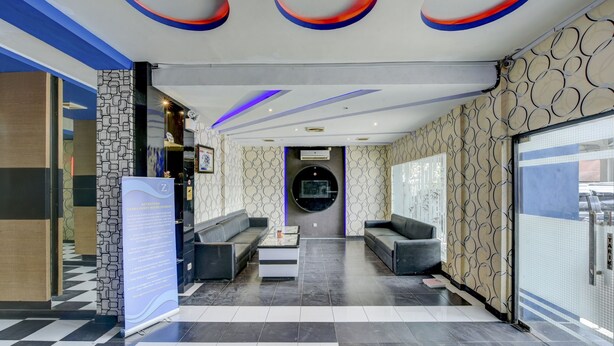 A modern lobby with a checkered floor, two sofas, a coffee table, and a circular wall feature. - OYO 4010 Zaara Guest House Syariah (Padang)