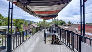 A covered outdoor area with a metal railing, a staircase, and a view of surrounding buildings and greenery. - OYO 4010 Zaara Guest House Syariah (Padang)