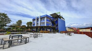 A multi-story building with a blue facade, outdoor seating area, and a visible staircase. - OYO 4010 Zaara Guest House Syariah (Padang)