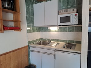 Een keuken met een magnetron, een spoelbak en een fornuis.
