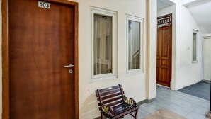 Un couloir avec une porte en bois portant le numéro 103, un banc et une autre porte en bois portant le numéro 104.