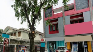 Une vue de rue avec une voiture blanche garée devant un immeuble à la façade rouge et grise.