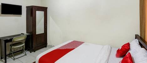 A bedroom with a bed, a desk, a chair, a wardrobe, and a flat-screen TV.