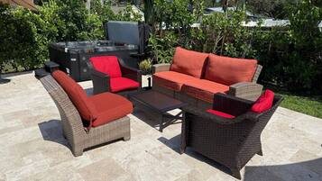 An outdoor patio with wicker furniture, a small table, and a grill.
