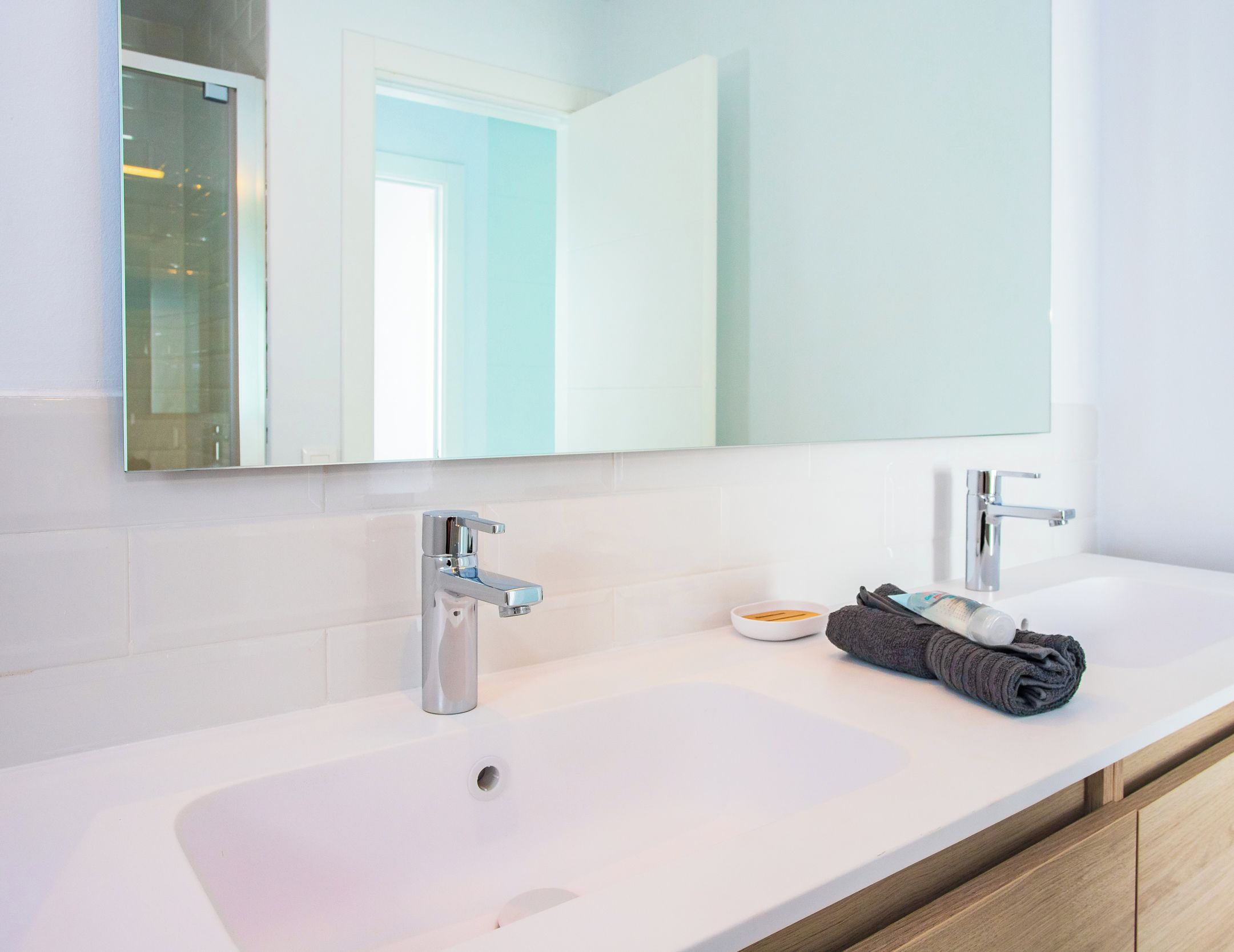 Une salle de bain moderne avec un grand miroir, deux lavabos et des meubles en bois.
