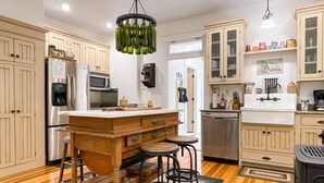 A kitchen with wooden cabinets, a central island with stools, a refrigerator, a microwave, and a dishwasher. - Beekeeper's Cottage - Hot Tub, Heated Pool, Dog-friendly, Downtown (Washington)