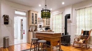 A kitchen with wooden stools, a central island, and a black stove. - Beekeeper's Cottage - Hot Tub, Heated Pool, Dog-friendly, Downtown (Washington)