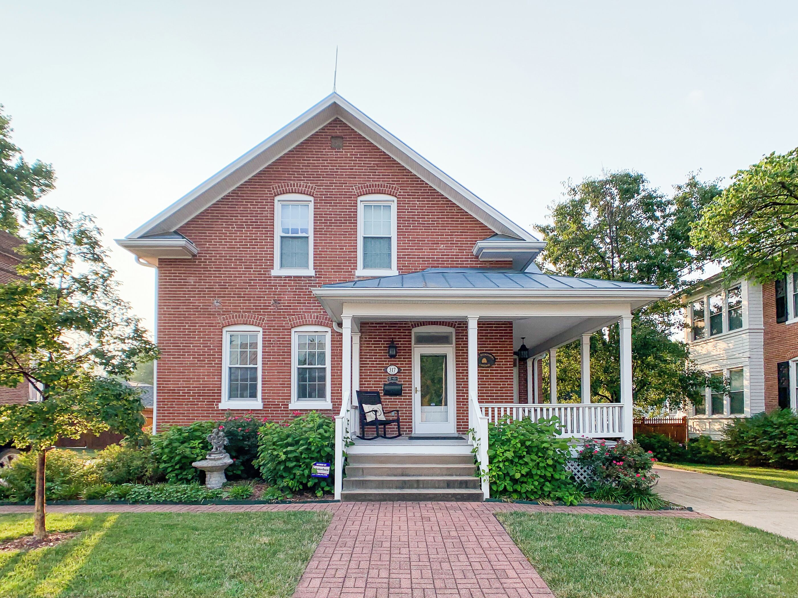 A two-story brick house with a front porch, a mailbox, and a well-maintained lawn.