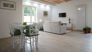 A modern living room with a dining area, wooden ceiling beams, a flat-screen TV, and potted plants. - Relais Gregorio - Villa with private pool and garden in Irpinia (Paternopoli)