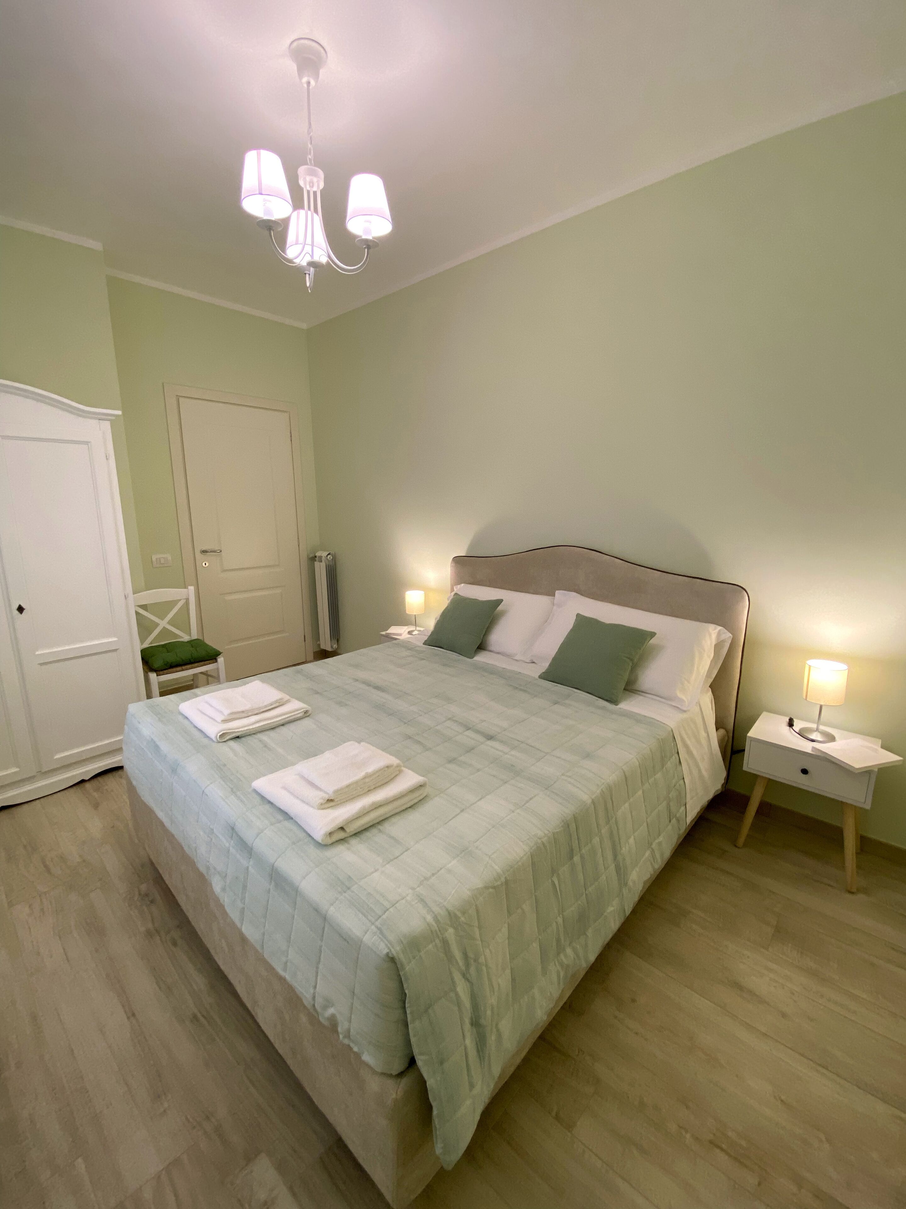 A neatly made bed with folded towels, a bedside lamp, and a nightstand.