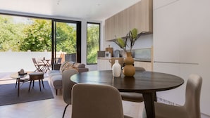 Een moderne keuken met een eethoek, grote ramen en uitzicht op groen.