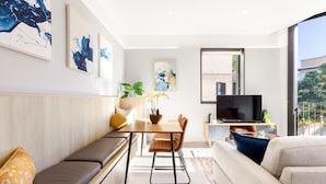 Een moderne woonkamer met een bank, een eettafel met stoelen en een televisie.