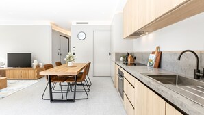 Een moderne keuken met houten kastjes, een marmeren aanrechtblad en een ingebouwde oven.