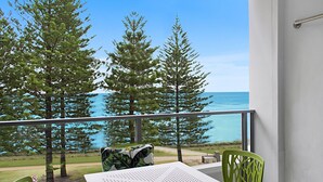 A balcony with a table and chairs, overlooking a body of water and trees. - Rainbow Pacific Unit 12 - Beachfront unit a great spot for a family beach holiday with Wi-Fi Inc. (Coolangatta)
