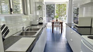 A modern kitchen with a large window, a dining area, and a view of trees. - Rainbow Pacific Unit 12 - Beachfront unit a great spot for a family beach holiday with Wi-Fi Inc. (Coolangatta)
