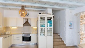 Une cuisine moderne avec des meubles blancs, un four encastré et un placard à portes vitrées.