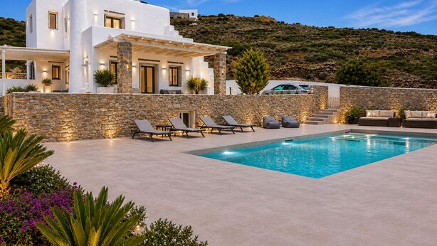 Une villa moderne dotée d’une piscine, de murs en pierre et offrant une vue sur les collines.