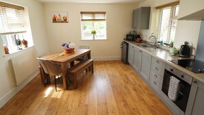 A kitchen with a wooden table, a built-in oven, and a window with blinds. - The New Build (Louth)